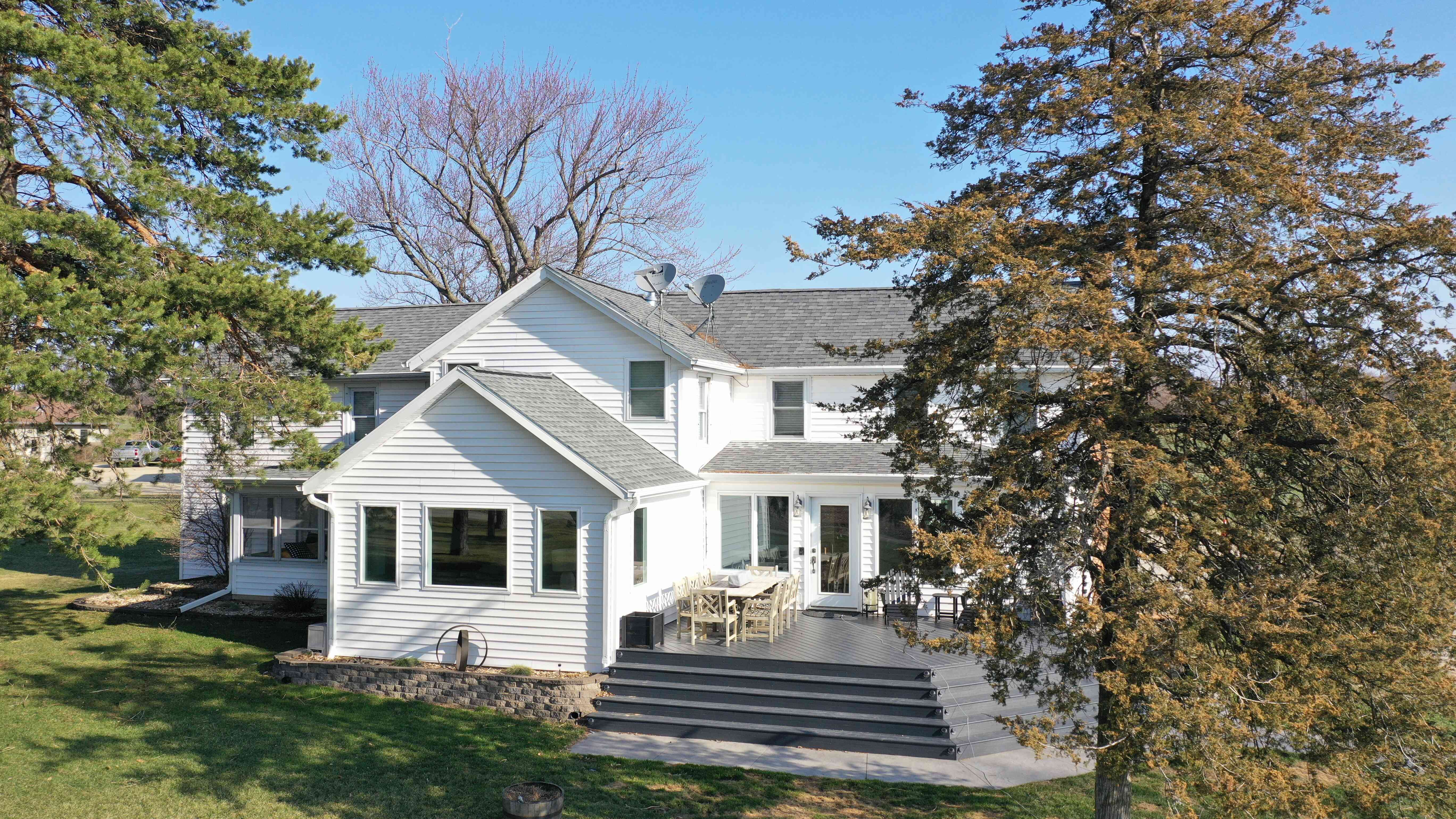 Before renovation showing older white farmhouse exterior with outdated siding, roof, and chimney