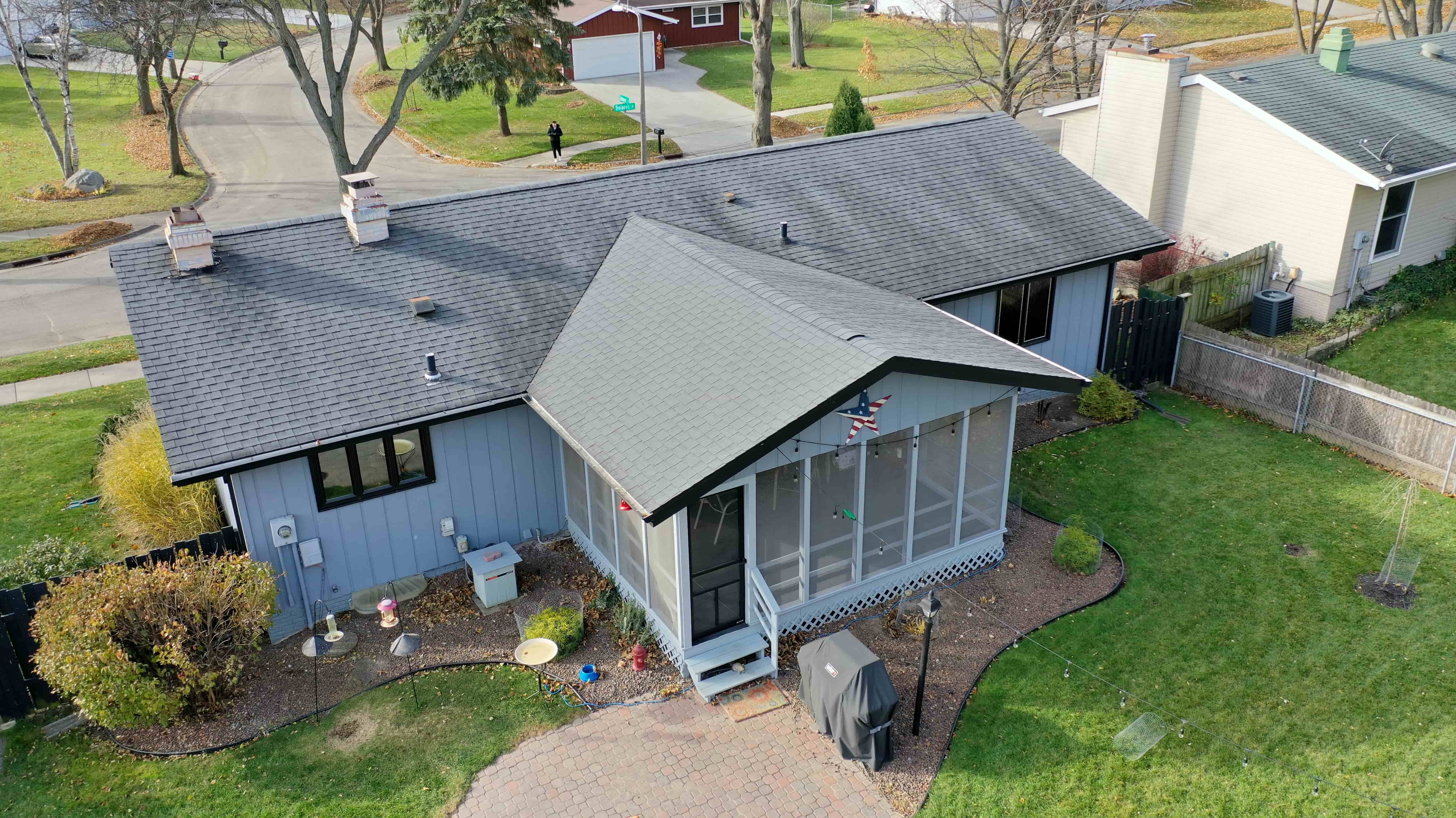 Before exterior renovation showing outdated roof, siding, and windows on residential home