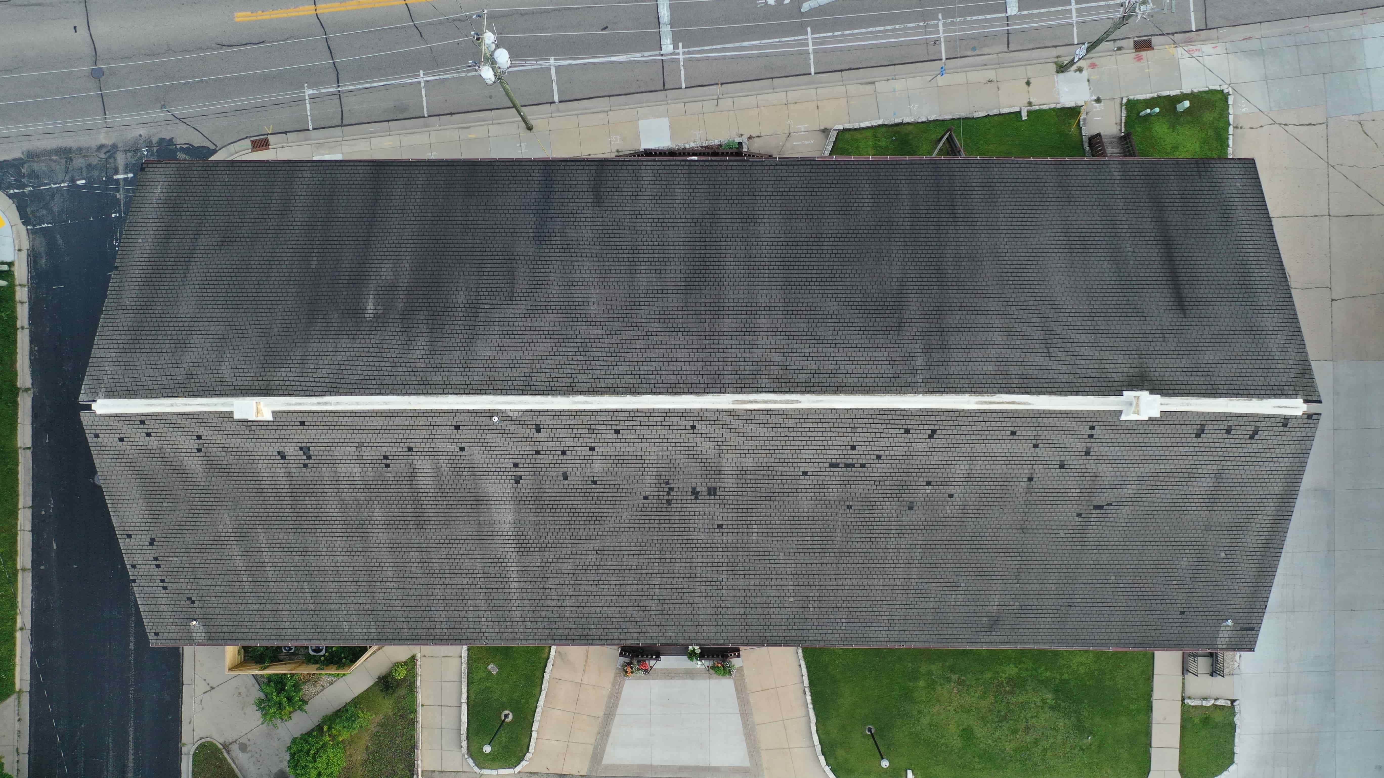 Before roof replacement on wedding venue showing worn and aging shingles across large commercial roof